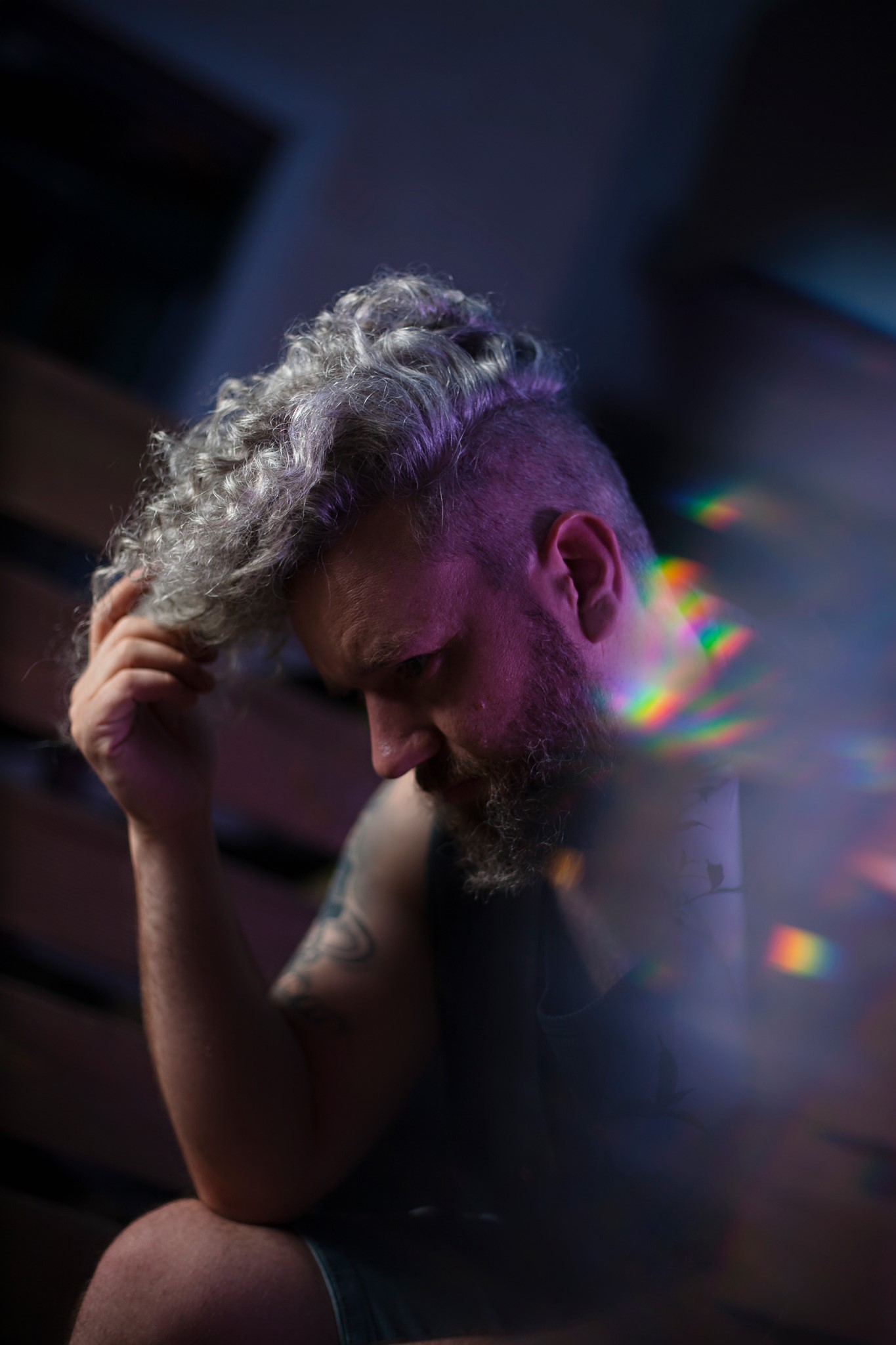 Eine Porträt eines Mannes mit grauem lockigen Haar im Halbschatten.